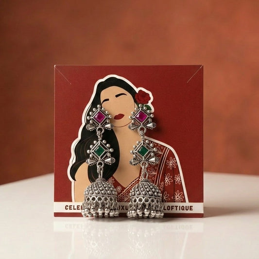 A refined blend of structure and sparkle, this piece captures the beauty of geometric elegance with a vibrant touch of color. The dual-stone design flows seamlessly into a classic dome jhumka, creating a graceful movement that feels both modern and rooted in tradition.