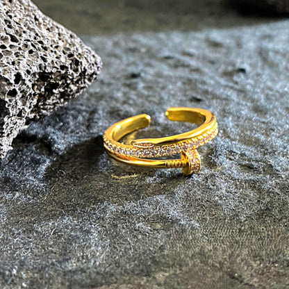 Crafted with a smooth high-polish gold-tone finish, this open cuff-style ring features a sleek nail-inspired design adorned with delicate micro-stone detailing that catches the light effortlessly. The adjustable open structure ensures a comfortable fit, making it perfect for statement styling or everyday luxury layering.