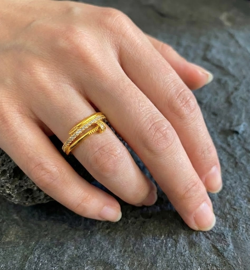 Crafted with a smooth high-polish gold-tone finish, this open cuff-style ring features a sleek nail-inspired design adorned with delicate micro-stone detailing that catches the light effortlessly. The adjustable open structure ensures a comfortable fit, making it perfect for statement styling or everyday luxury layering.